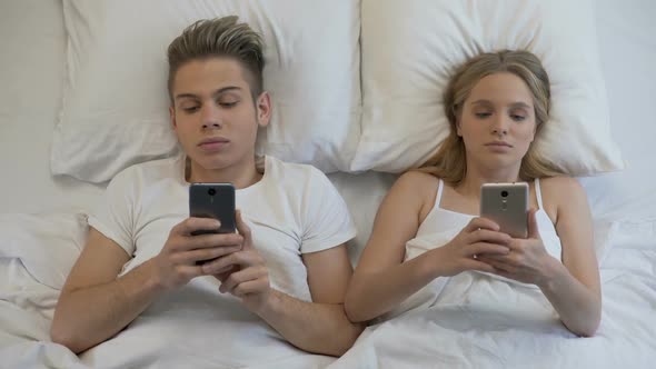 Married Couple Surfing Internet on Smartphones in Bed