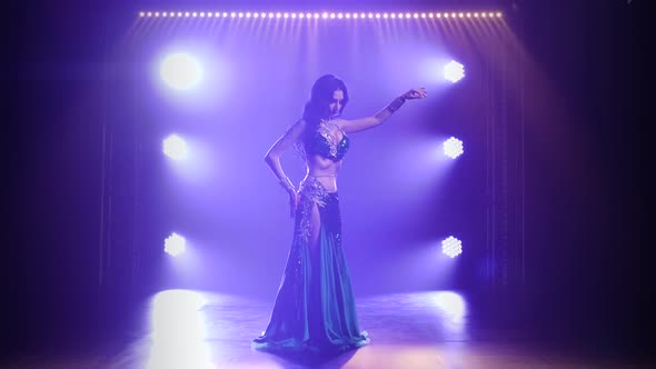 Girl in a Green Shiny Oriental Costume Performs Classical Belly Dance. Shot in a Dark Studio with