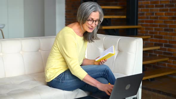 Concentrated Mature Grayhaired Woman in Glasses Using Laptop for Online Studying