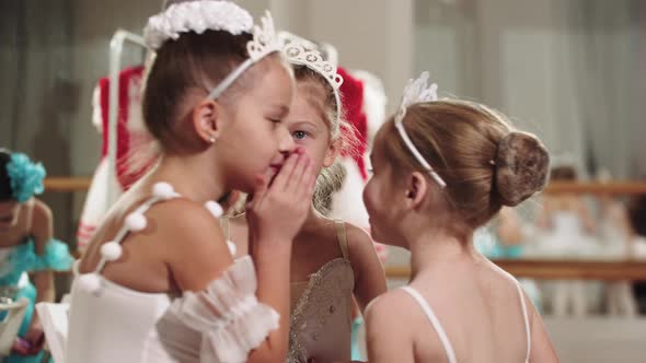 Three Little Ballet Girls Standing in the Studio and Whispering to Each Other