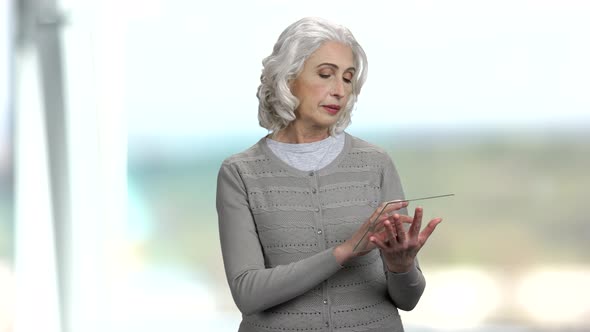 Senior Woman Using Glass Digital Tablet.