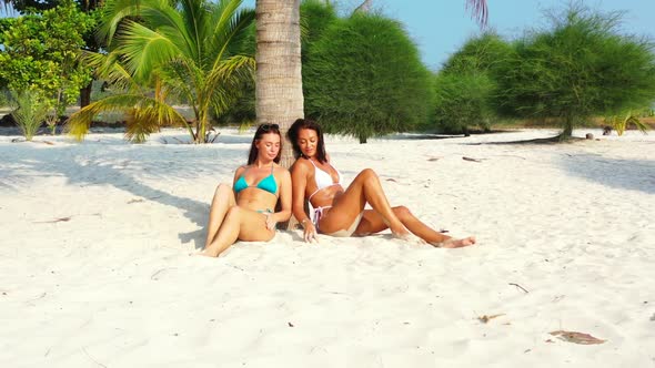 Ladies together best friends on idyllic tourist beach adventure by transparent ocean and clean sandy
