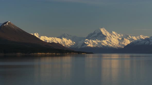 early morning panning shot of mt cook and a calm lake pukaki