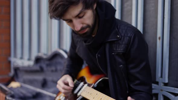 Man Playing on the Giutar with a Pick Outdoor