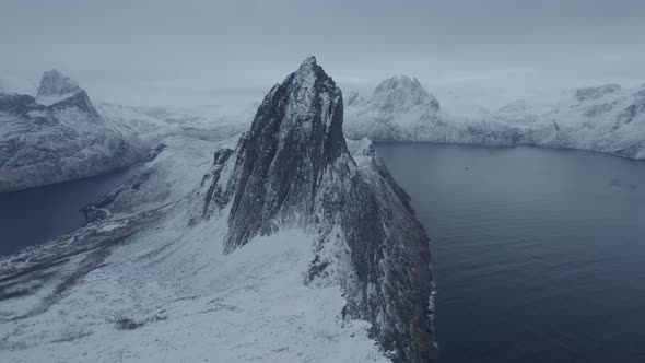 Aerial view of the Segla mountain and the Fjordgard town, in Senja, North Norway - pan, drone shot