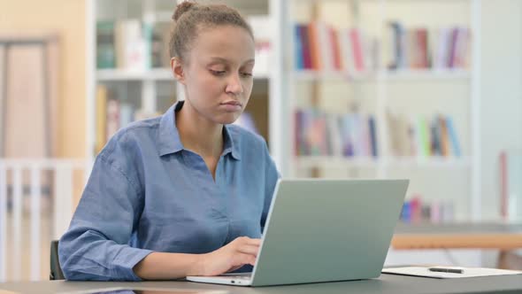 Tired African Woman with Laptop Having Neck Pain in Library