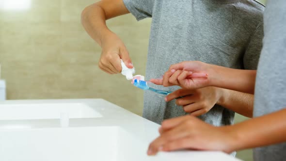 Siblings brushing their teeth in bathroom