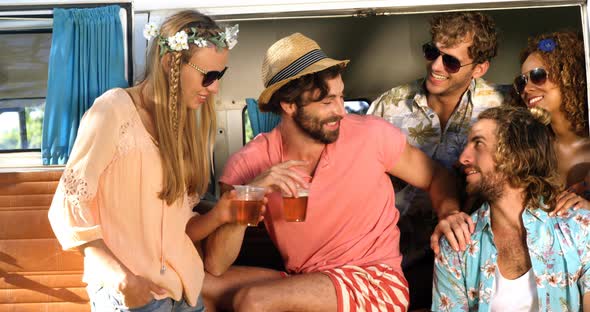 Group of friends drinking some beer and sitting on the van