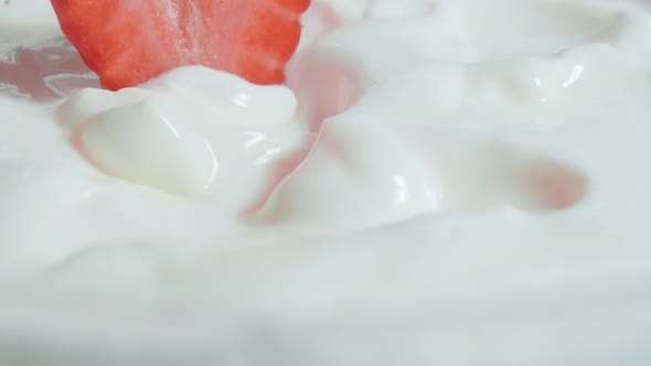 Fresh strawberries fall into yogurt. Organic ripe strawberry. Close up