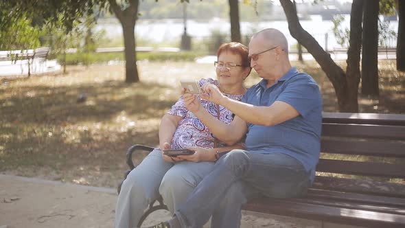 Mature Couple Taking Selfie Photo Sitting on a Bench Park