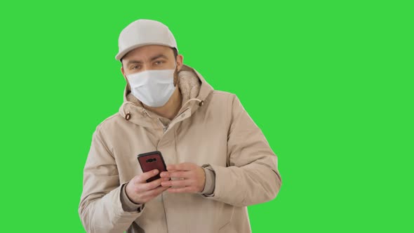 Young Casual Man Walking Making a Call Wearing Warm Clothes and Protective Mask on a Green Screen