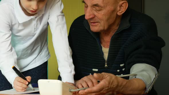 Caucasian grandson 7 years old helps grandfather over 70 years old to measure blood pressure while a