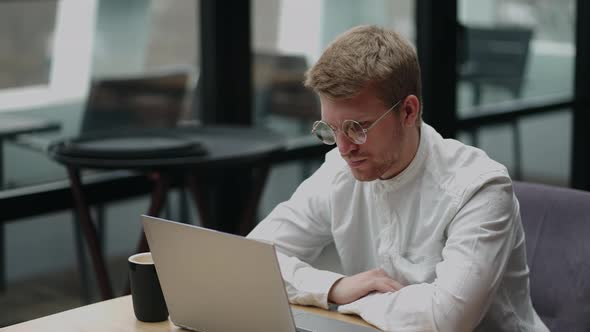 Clever Man is Working with Laptop in Coworking or Office Reading News or Agreement on Laptop Display