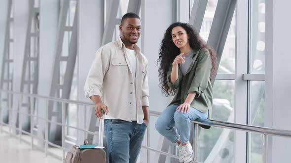 Multiracial Couple Hispanic Woman and African Man Sitting Standing at Airport with Suitcase Talking