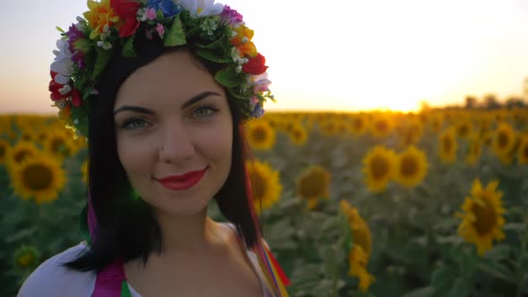 Portrait of Young and Beautiful Woman in Sunflower Field on Sunset. Lady in Flower Wreath. Slow