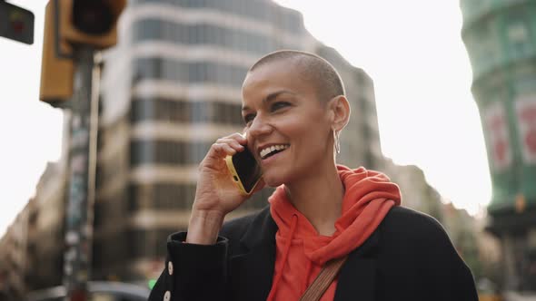 Positive bald woman talking by mobile