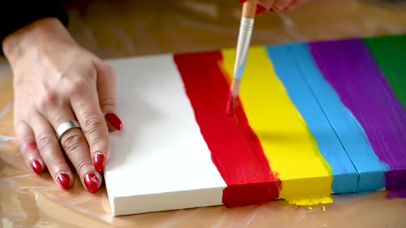 A woman painting colorful stripes on a canvas