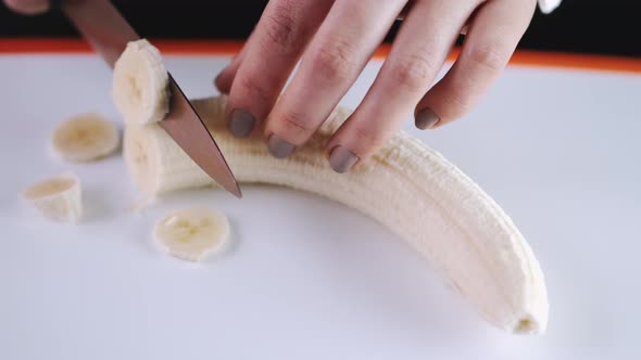 The Chef Is Cutting a Banana on a Cutting Board