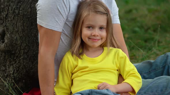 Girl Sits on Green Lawn in Summer Park