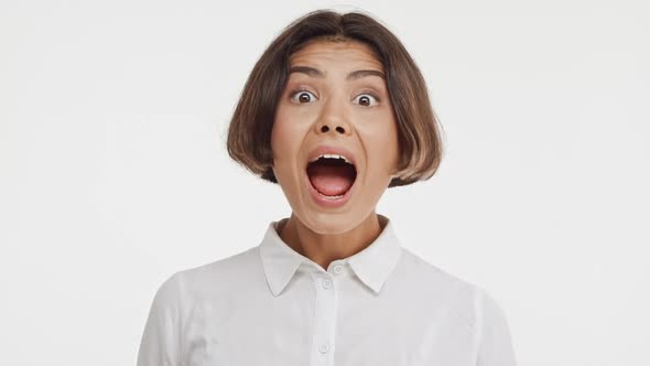 Young Beautiful Brunette East Asian Female in Shirt Screaming Wow in Surprise on White Background in