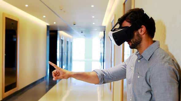 Male executive using virtual reality headset in corridor