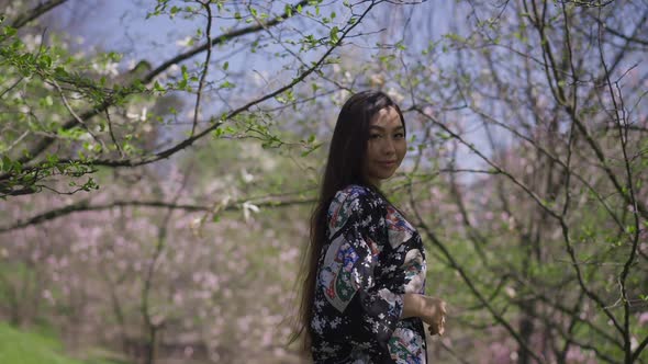 Back View of Happy Slim Beautiful Asian Young Woman Walking in Spring Park Turning to Camera Smiling