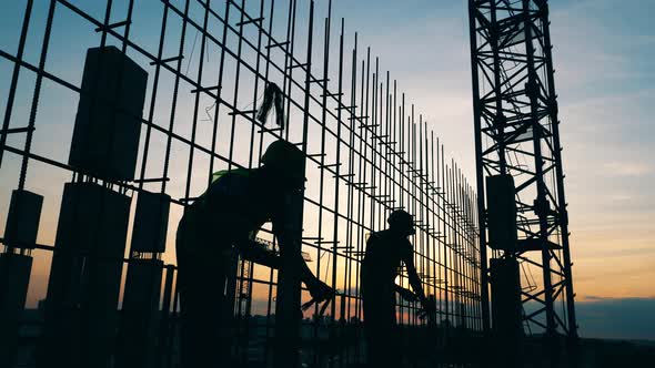 Male Workers Build a House on a Sunset Background