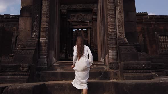 Lady going up the stairs to ancient palace in Wat Phou ruined Khmer Hindu Temple complex Laos Asia