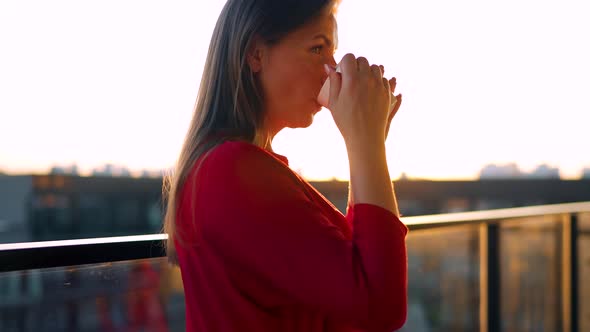 Woman Drinking Coffee or Tea While Standing on the Balcony and Admire the Sunset