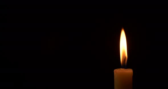 Closeup Burning Single Candle Flame Isolated on Black Background with Copy Space