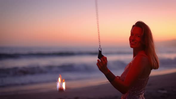 Woman fire dancer spinning flames at the beach