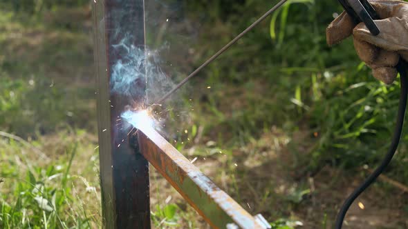 Close View Builder Welds Rail To Pole with Sparks and Smoke