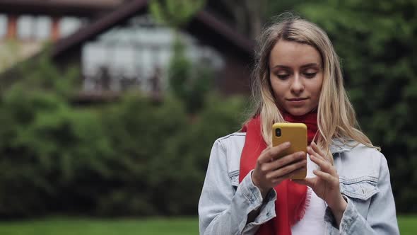 Portrait of Young Beautiful Woman Wearing in the Red Scarf Using Smartphone, Checking Phone and