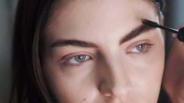 Close-up of a Makeup Artists Hand Apply Fixing Transparent Gel 