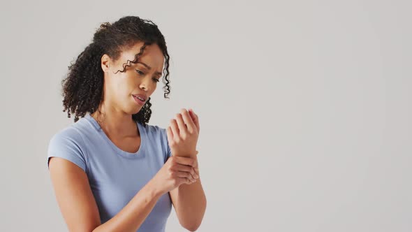 Video of biracial woman touching her wrist on white background