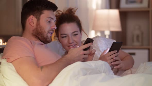 Happy Couple Using Smartphones in Bed at Night 57