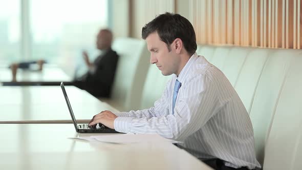 Businessman using laptop and looking at camera