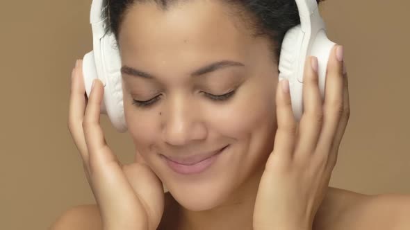 Beauty Portrait of Young African American Woman Dancing and Enjoying Music in Big White Headphones