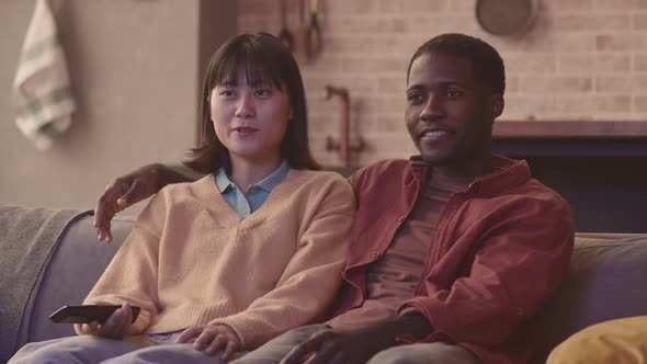 Diverse Couple Watching TV at Home