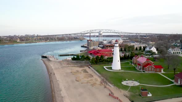 Fort Gratiot Lighthouse in Port Huron, Michigan with Blue Water Bridge in background drone videoing