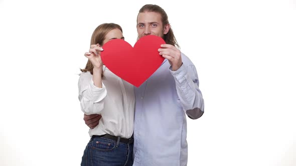 Slow Motion of Couple Playing with a Red Paper Heart and Kissing.