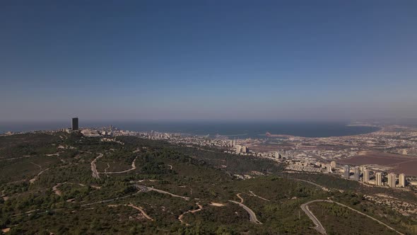 Green hills with roads and traffic next to the port city of Hairfa in Israel, horizon with sea and b