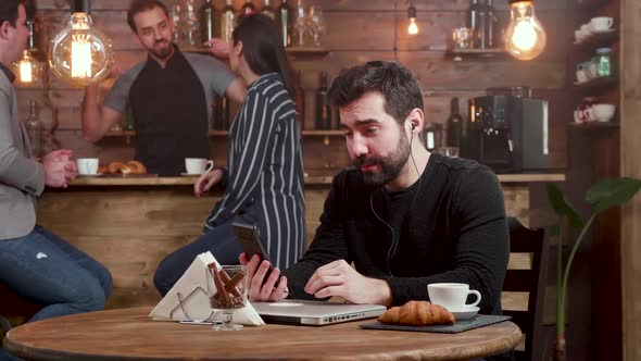 Young Handsome Man Engaged in a Video Call While Serving His Coffee in a Cafe