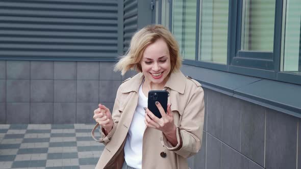 Portrait of Happy Business Woman Celebrate Success Win on Smartphone Standing Outdoors in Downtown