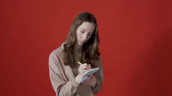 Young Inspired Woman Pensively Thinks and Making Notes in Paper Notebook