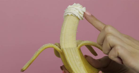 Woman Hand Holds Banana with Whipped Cream on Fruit. Finger Touches the Cream