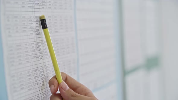 Female Hand with Pencil Pointing at Timetable