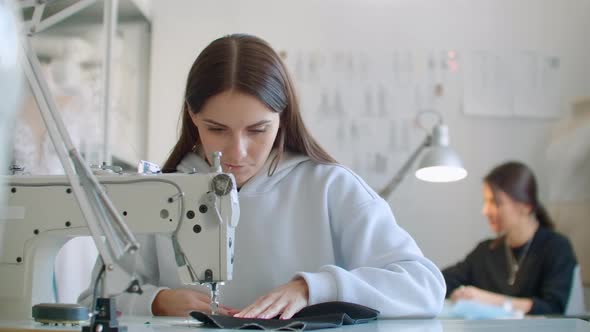 Young Womans Hands Seamstress Sitting and Sews on Sewing Machine in Creative Designer Studio