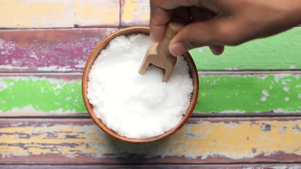 Hand Pick Coarse Salt i with a Spoon From a Bowl on Table