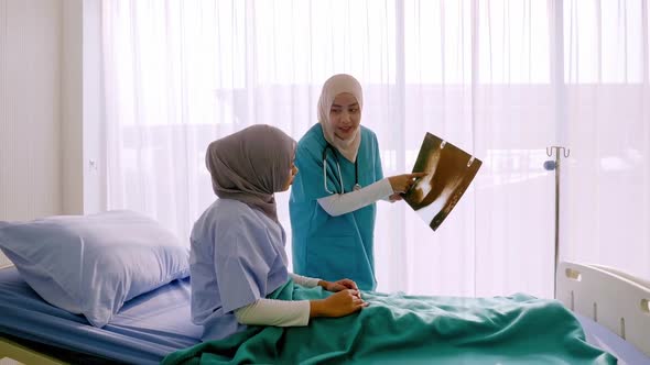 Expert doctor examining and explaining x-ray film to patient in hospital ward